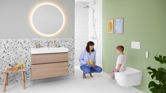 Žena i dijete u šarenoj kupaonici s ogledalom Geberit Option i Geberit AquaClean Alba tuš WC uređajem