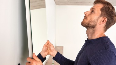Osoba vješa ogledalo Geberit Option tijekom renoviranja kupaonice